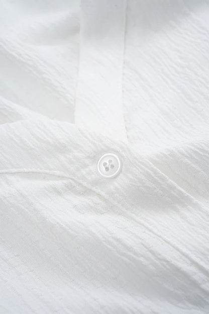 Camisa CASANDRA asimétrica de manga larga sin espalda con botones.